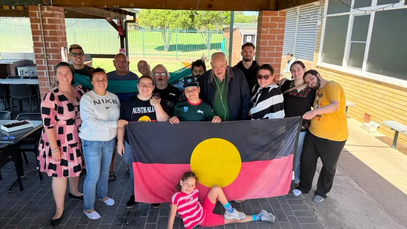 Tegrity staff and participants together holding the Aboriginal flag at the weekly rec group in Sydney