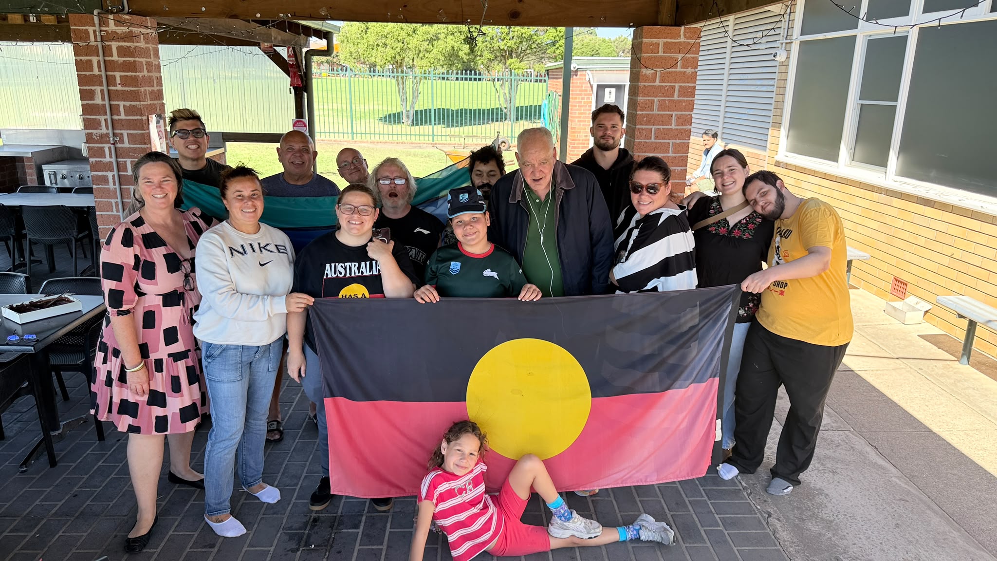 Tegrity staff and participants together holding the Aboriginal flag at the weekly rec group in Sydney