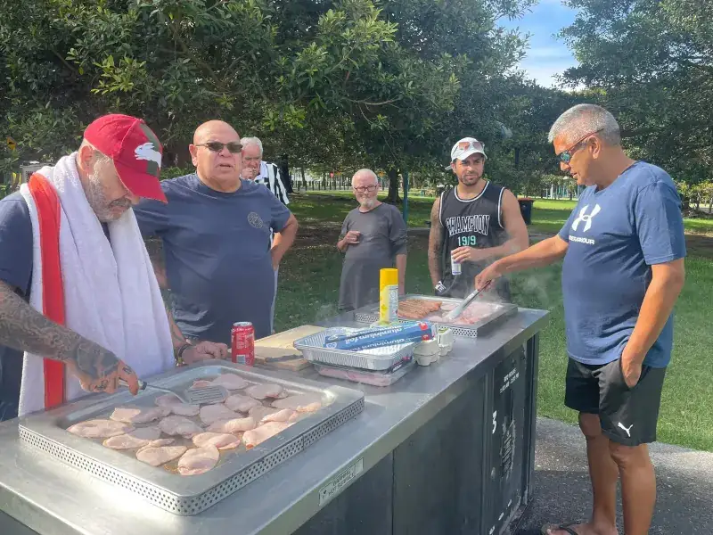 Support workers and participants at a community barbecue in a Sydney park