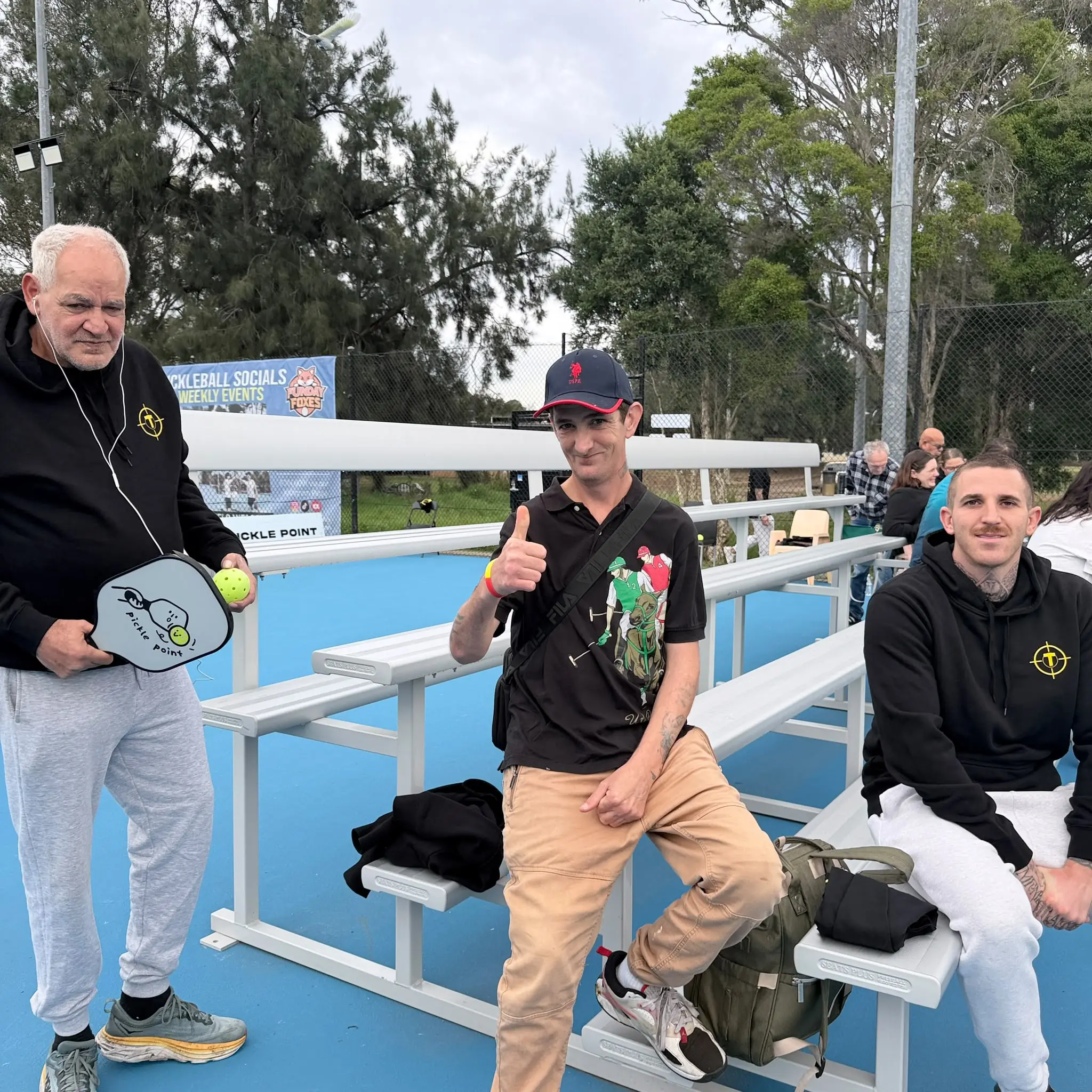 Tegrity participants and support workers relaxing courtside at the pickleball day