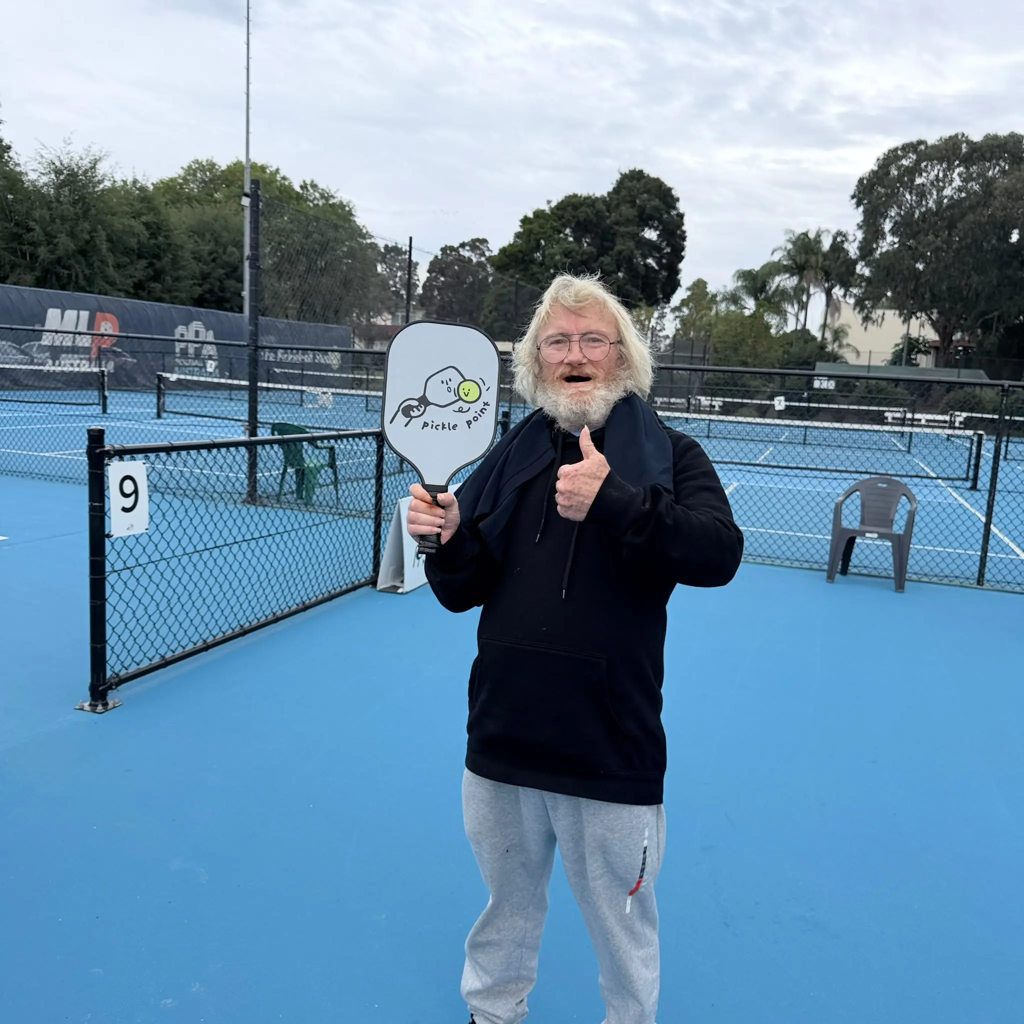 A smiling Tegrity participant giving a thumbs-up with a pickleball paddle at Pickle Point Sydney