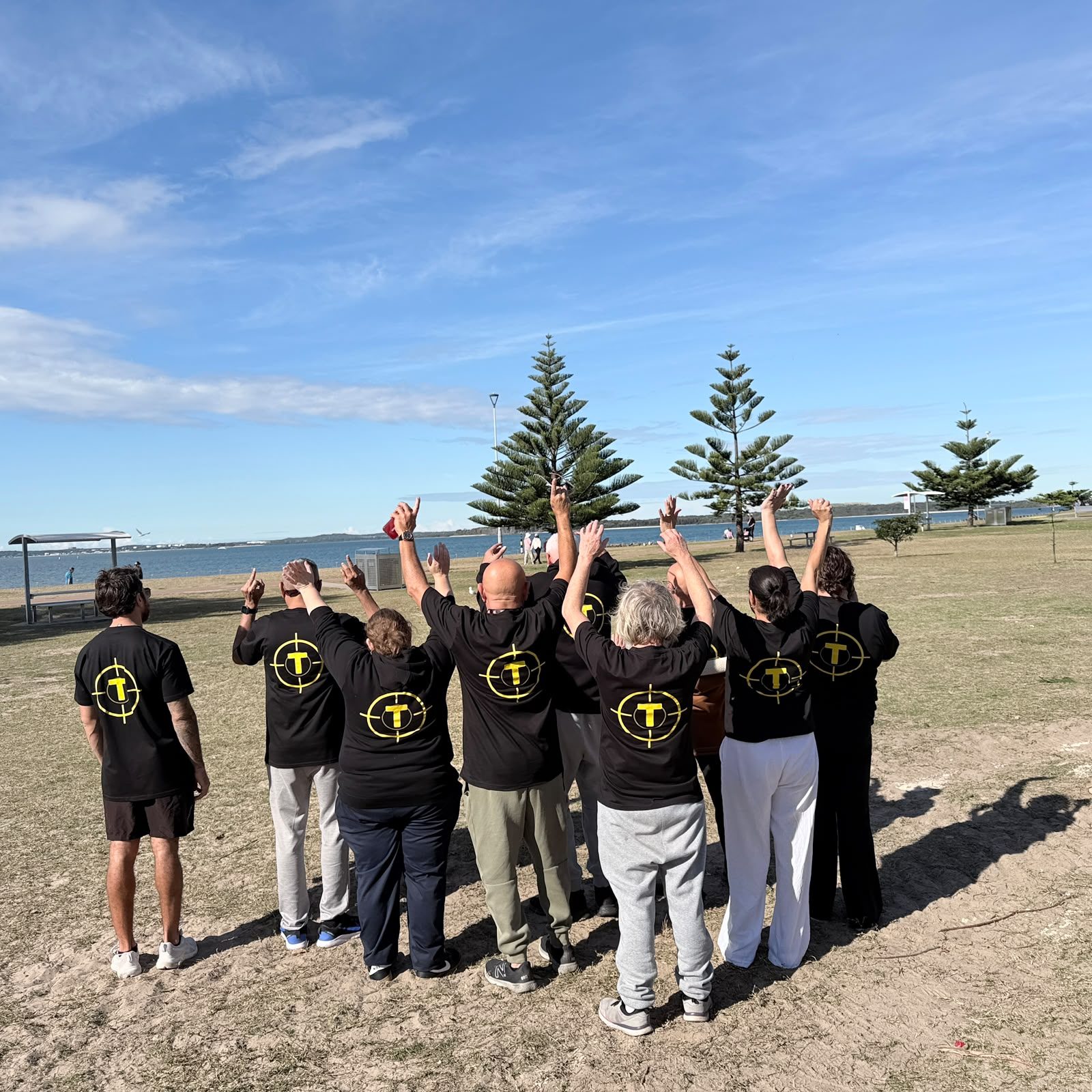 The Tegrity team in branded shirts raising their arms together on the beach